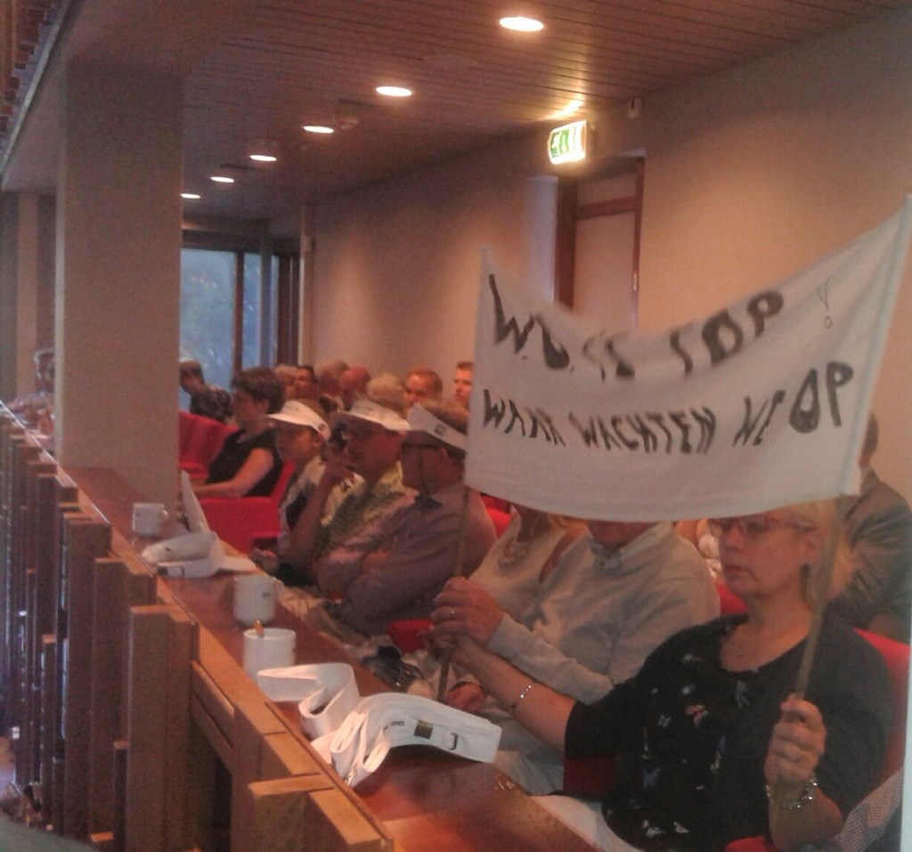 demonstranten met spandoeken in de raadszaal.