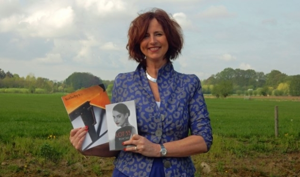 Heleen Smit met haar boek 'Lot 33' en de catalogus van veilinghuis Sotheby's in Parijs. Op de omslag van de gids staat een foto van het bureau, dat op haar zolder stond. De vondst van het bureau zorgde voor een spannende zoektocht naar de herkomst ervan. FOTO: Asta Diepen Stöpler.