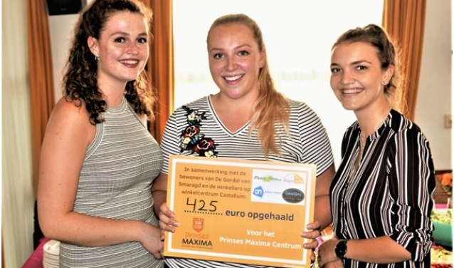Lilian, in het midden, en twee vriendinnen tonen de cheque