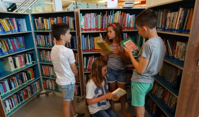 Lars, Job, Willemijn en Amélie van groep 7 van de Delteykschool zoeken boeken uit