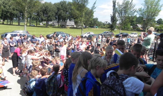 De kinderen verlaten de school door een tunnel van armen en handen.