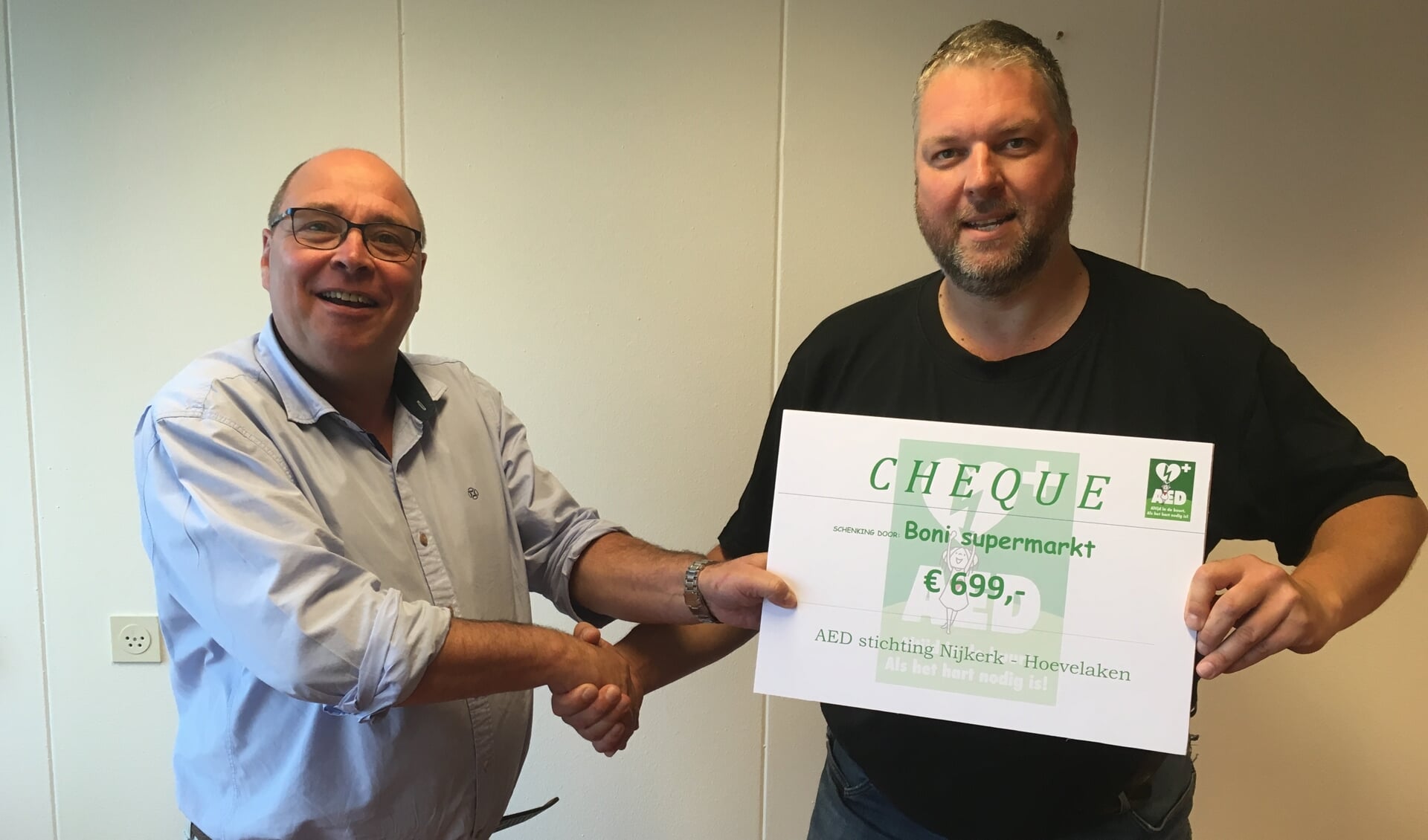 Marcel Bakker van de AED Stichting neemt de cheque in ontvangst van Dhr. Spierdijk,hoofd logistiek Boni Nijkerk 