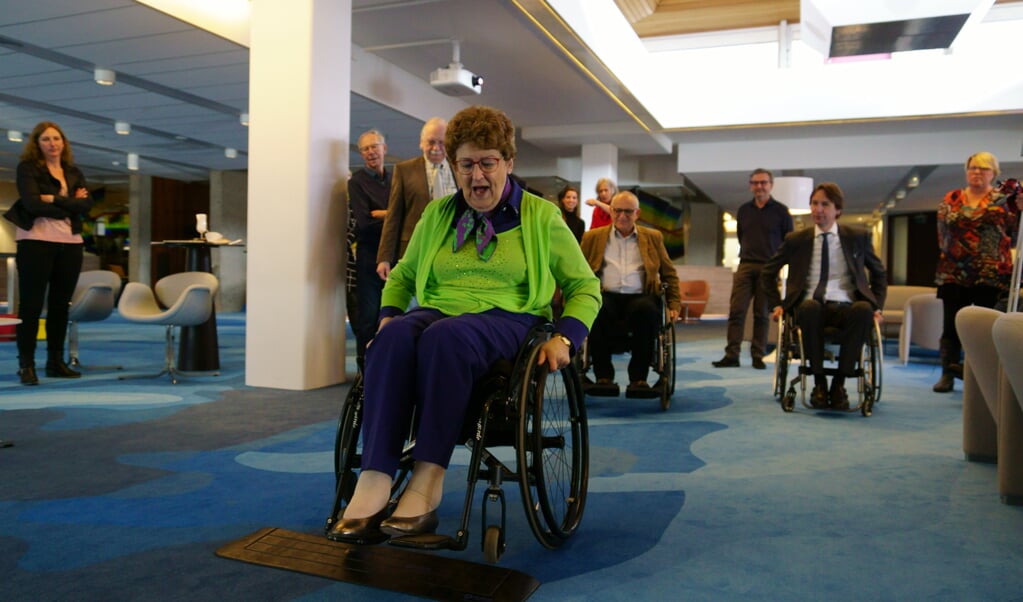 Corrie van Hugten doet oefenparcours rolstoelgebruik in raadhuis een keer voor. 