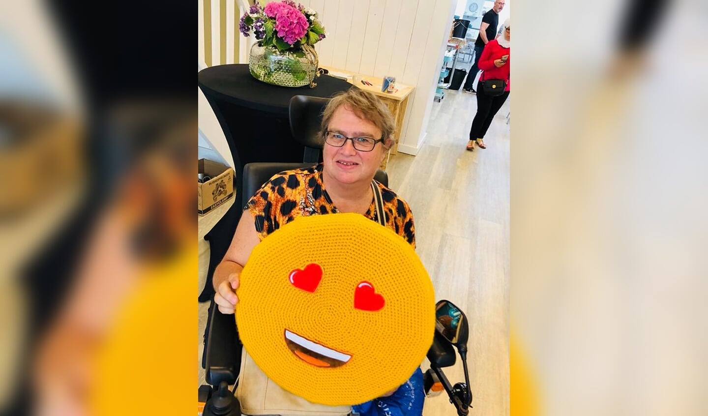 Joke Wouda met de reuze-smiley, die in de etalage van Wilma's Naald en Draad hangt.