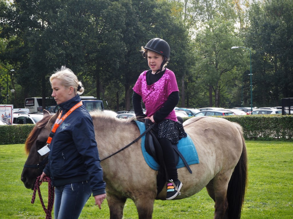 Lieveke, in haar danskleding, glunderend op een paard van Pegatrust.