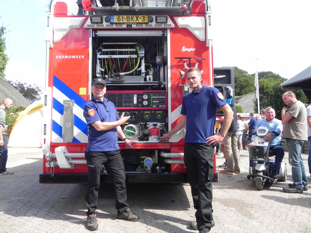 Huidig en opvolgend postcommandant van den Dikkenberg en van Wijk tonen trots hun nieuwe brandweerwagen.