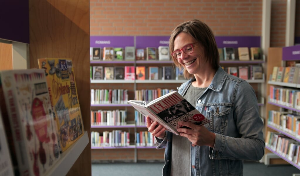 Thalita Boogaard van de bibliotheek snuffelt alvast even in een popgeschiedenisboek van Lex Harding.