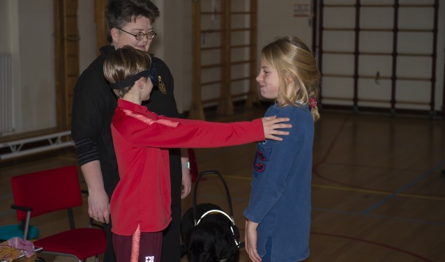 Dominiek Bos met haar geleidehond Nike laat kinderen met een blinddoek ervaren hoe het is om blind te zijn