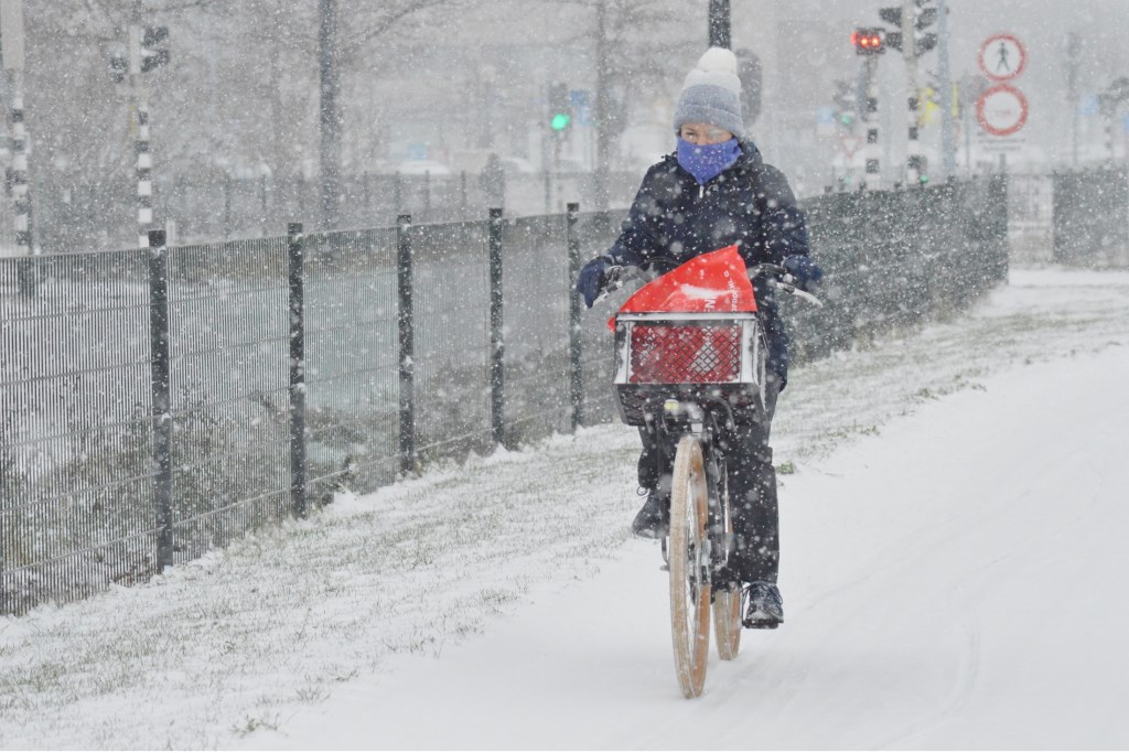 Een fietser trotseert dinsdagmiddag een sneeuwbui.