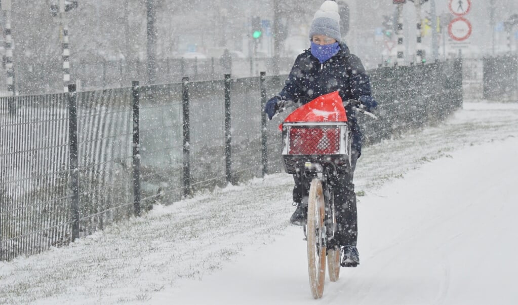 Een fietser trotseert dinsdagmiddag  een sneeuwbui.