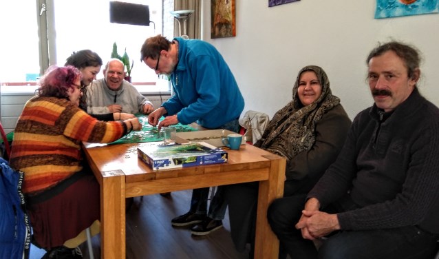 Bezoekers van de Inloop zijn fanatiek aan het puzzelen.
