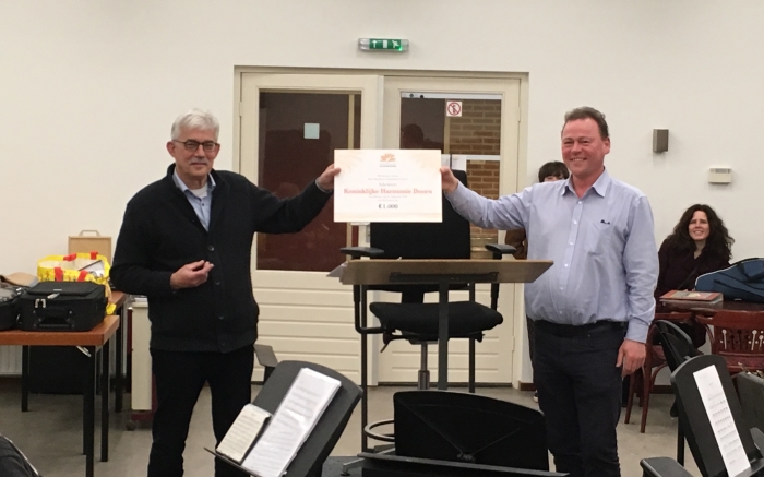 Voorzitter Huub Schouenberg (links) overhandigt cheque aan de dirigent Casper Dik (rechts)