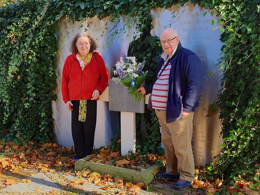 Ronnie en Denise Strang leggen een wit-blauw boeket bloemen bij het monument van neef Walter Strang.