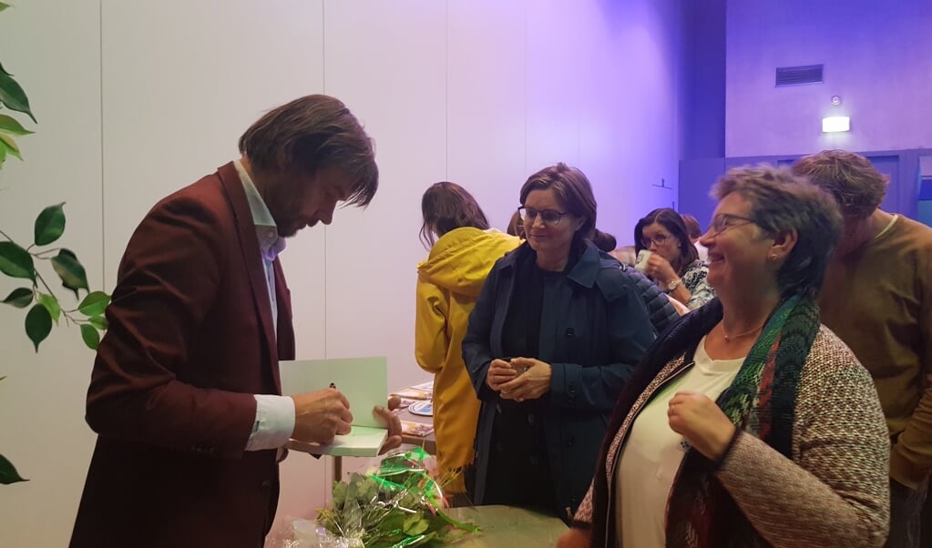 Wethouder Van Dijk laat haar boek signeren door Steven Pont. 