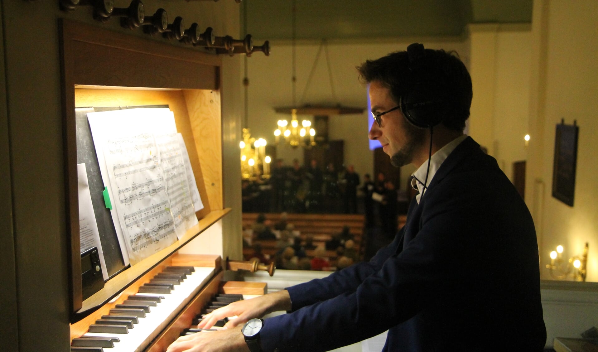 Arjan Veen bespeelt het orgel.Op de achtergrond is voor de preekstoel het koor Voci Vocal te zien