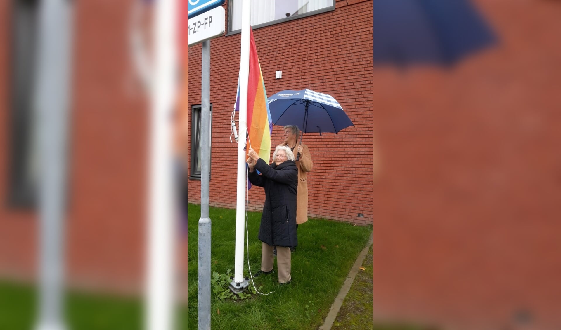 De 101-jarige Beppie van der Werf hijst de regenboogvlag.