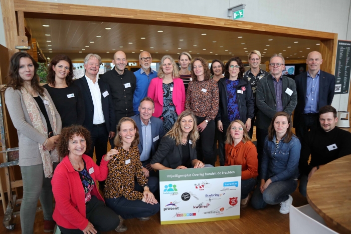 De leden van het Vrijwilligersplus Overleg poseren met wethouder Van Eijk (rechtsboven) na de ondertekening van de samenwerkingsovereenkomst.