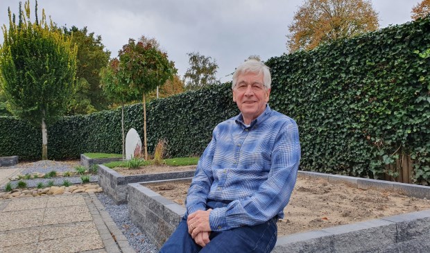 Cees op de rand van een lege plantenbak in zijn pas aangelegde tuin. Hij zoekt mensen die het op zijn kosten willen vullen.