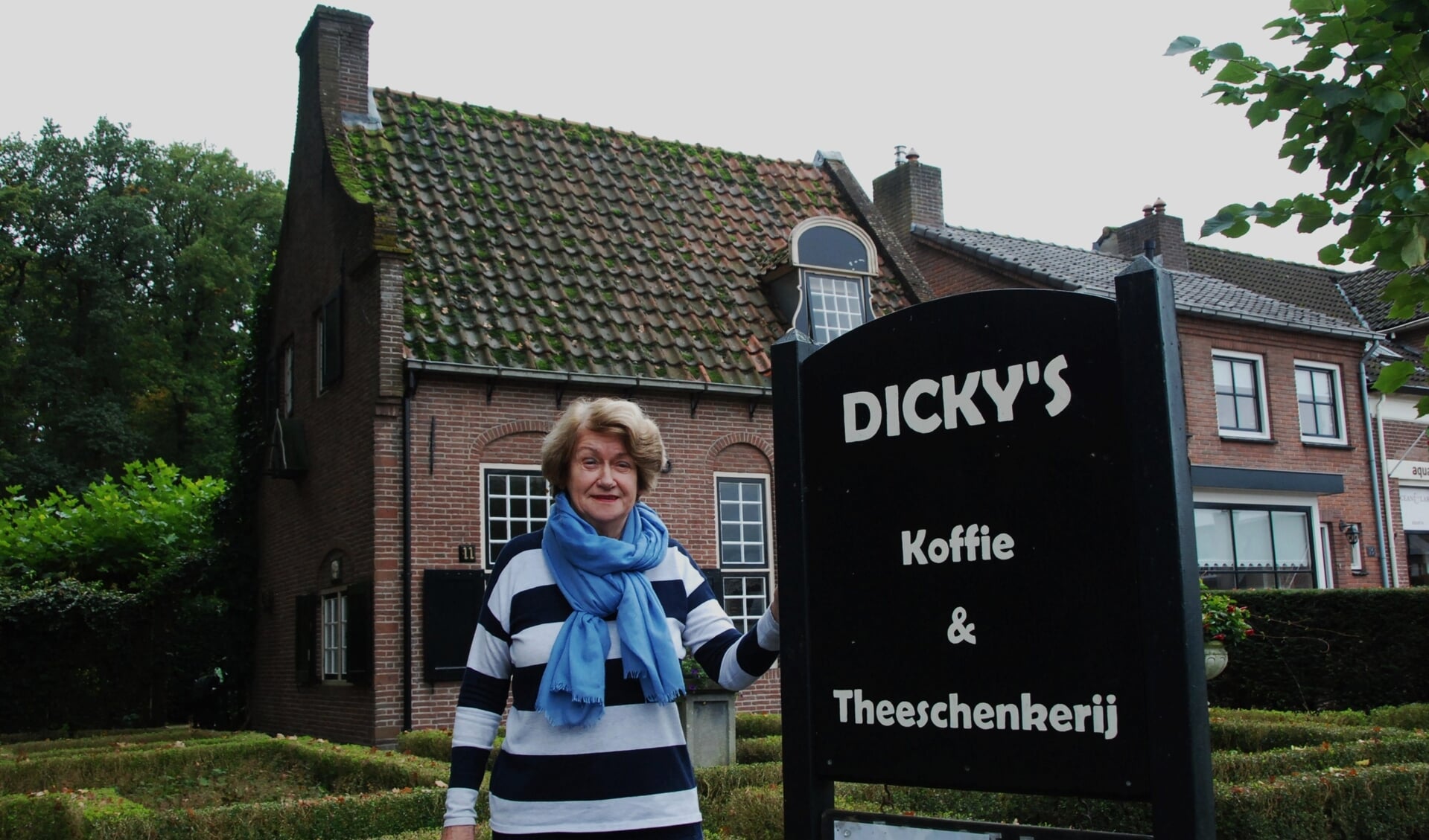 Dicky van Mourik bij het bord van haar Theeschenkerij, dat binnenkort verdwenen is.