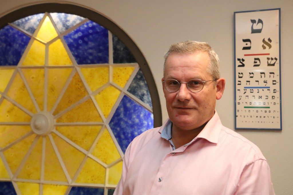 Wilbert Breugem op de bovenste verdieping van Kaasschieter in Barneveld, waar een raam herinnert aan de geschiedenis. Het pand was voorheen een joodse synagoge.