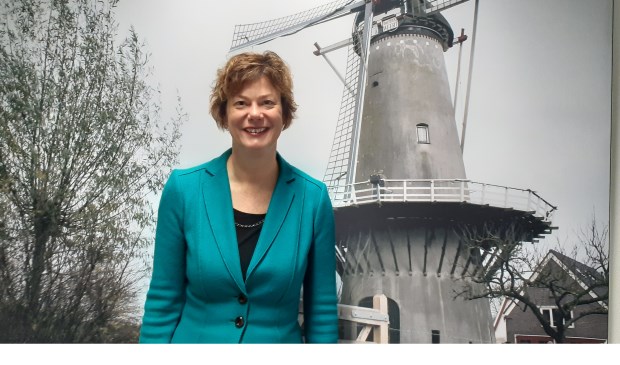 Wethouder Erika Spil bij een poster van de molen van Werkhoven op het gemeentehuis