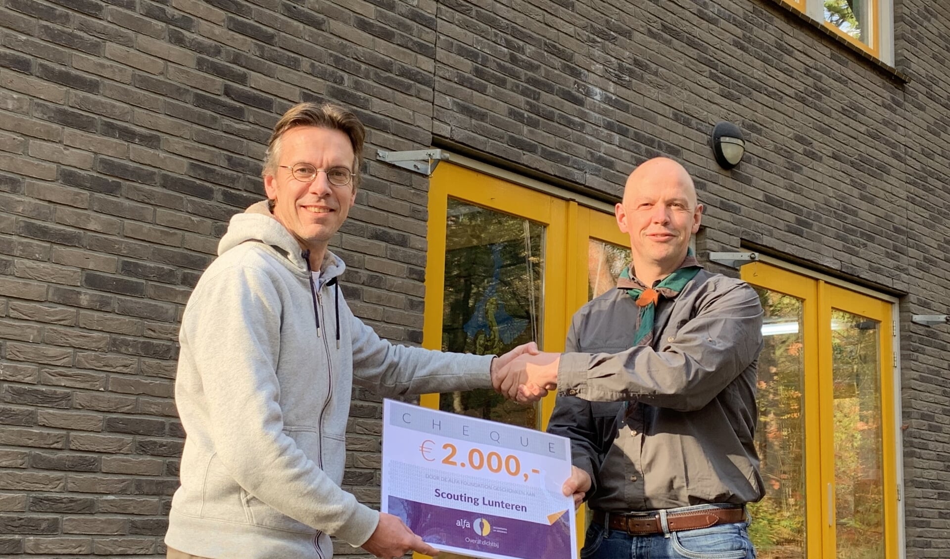 Voorzitter Jeroen Zieleman van Stichting Scouting Lunteren ontvangt een cheque van Frank van Ee van Alfa