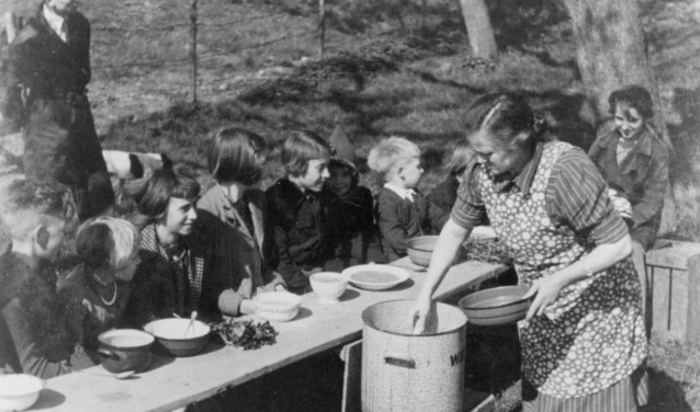Mevrouw Marsman deelt eten uit aan kinderen op de Rijndijk in Wijk bij Duurstede
