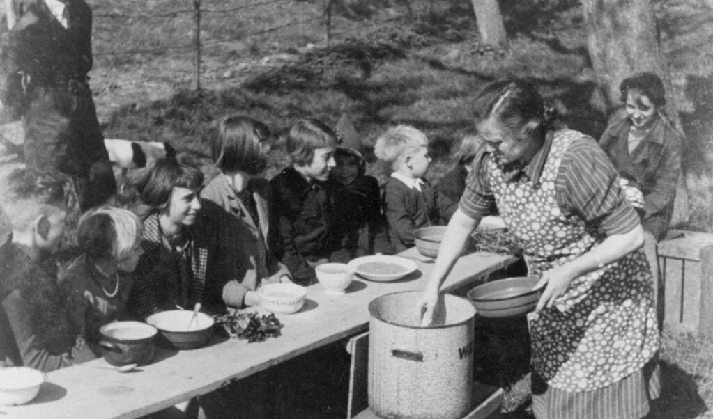 Mevrouw Marsman deelt eten uit aan kinderen op de Rijndijk in Wijk bij Duurstede