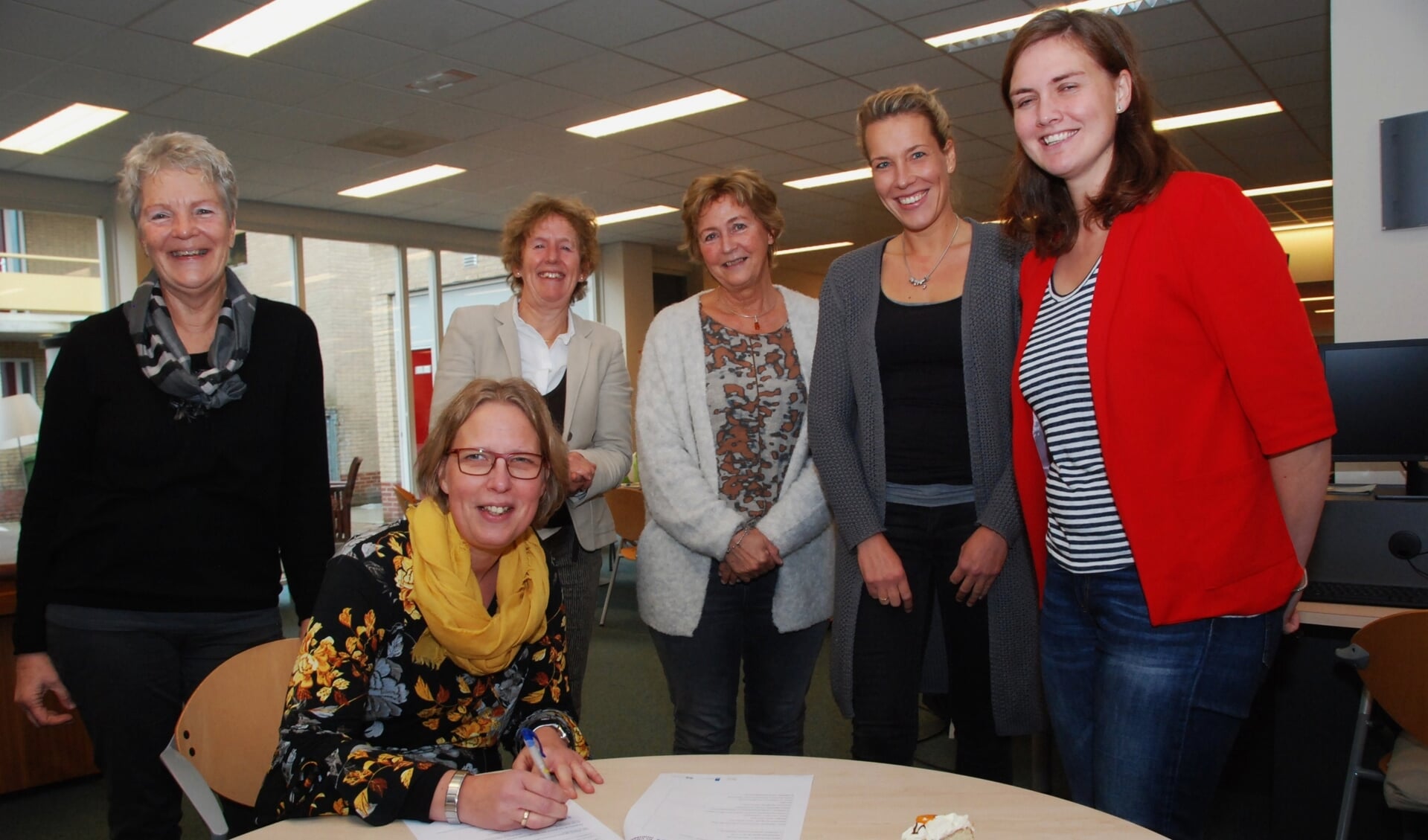 Terwijl andere partners toekijken, zet Rianne van Ginkel van SWO Scherpenzeel-Renswoude haar handtekening.