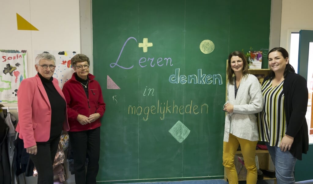 Directeur Gerda Mulder, Mevr. Ouwerkerk en juffen Anna Maarse en Saskia van Willigen bij het bord met de nieuwe slogan