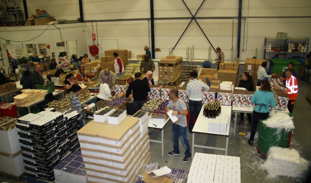 Medewerkers van het productiebedrijf pakken kerstpakketten in.