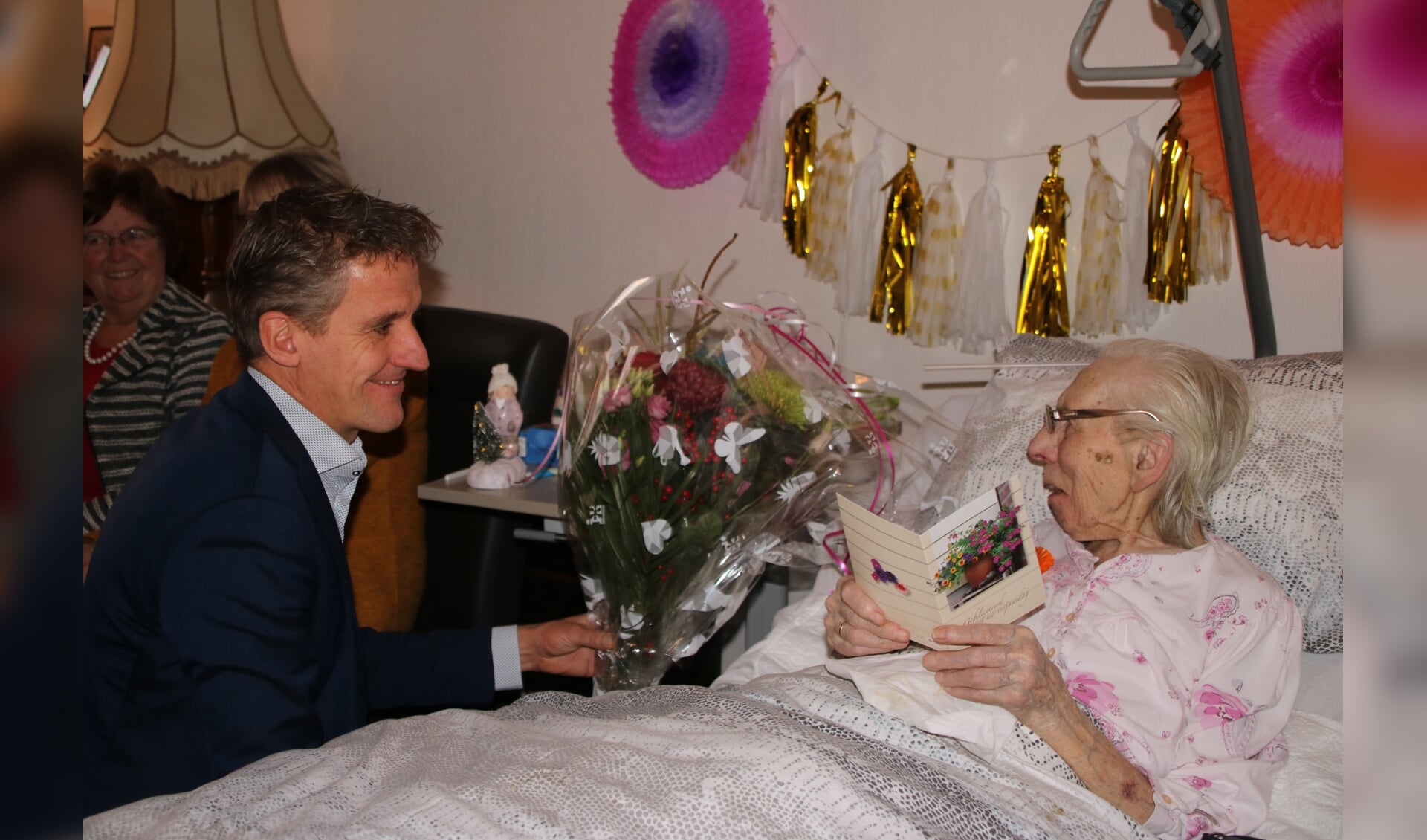 Mevrouw Meerkerk ontvangt bloemen van de bestuurder van De Lange Wei omdat zij 100 jaar is geworden