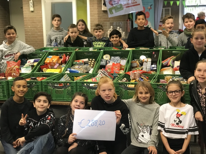 Leerlingen van OBS Twickel met de gevulde kratten en het opgehaalde bedrag voor de voedselbank