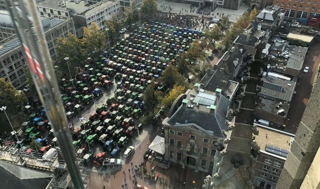 tractoren op een rij aan de markt en huizen van bovenaf bekeken