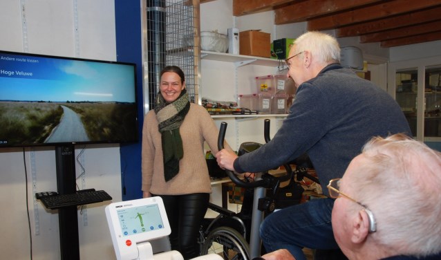 Annemien van Ginkel kijkt toe terwijl twee anderen een fietstocht over de Veluwe maken.