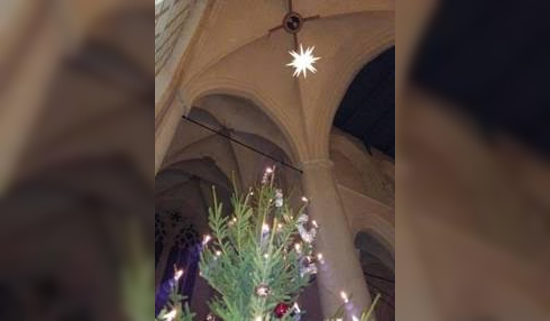 Boven de kerstboom hangt de kerstster in het kruisgewelf