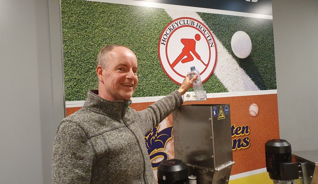 Mike staat op het punt een petflesje in de plastic shredder te laten vallen.