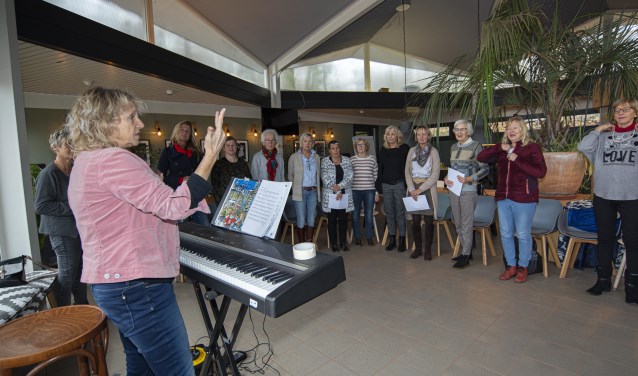 Kerstsongs zingen onder de enthousiaste leiding van Annelies Smit