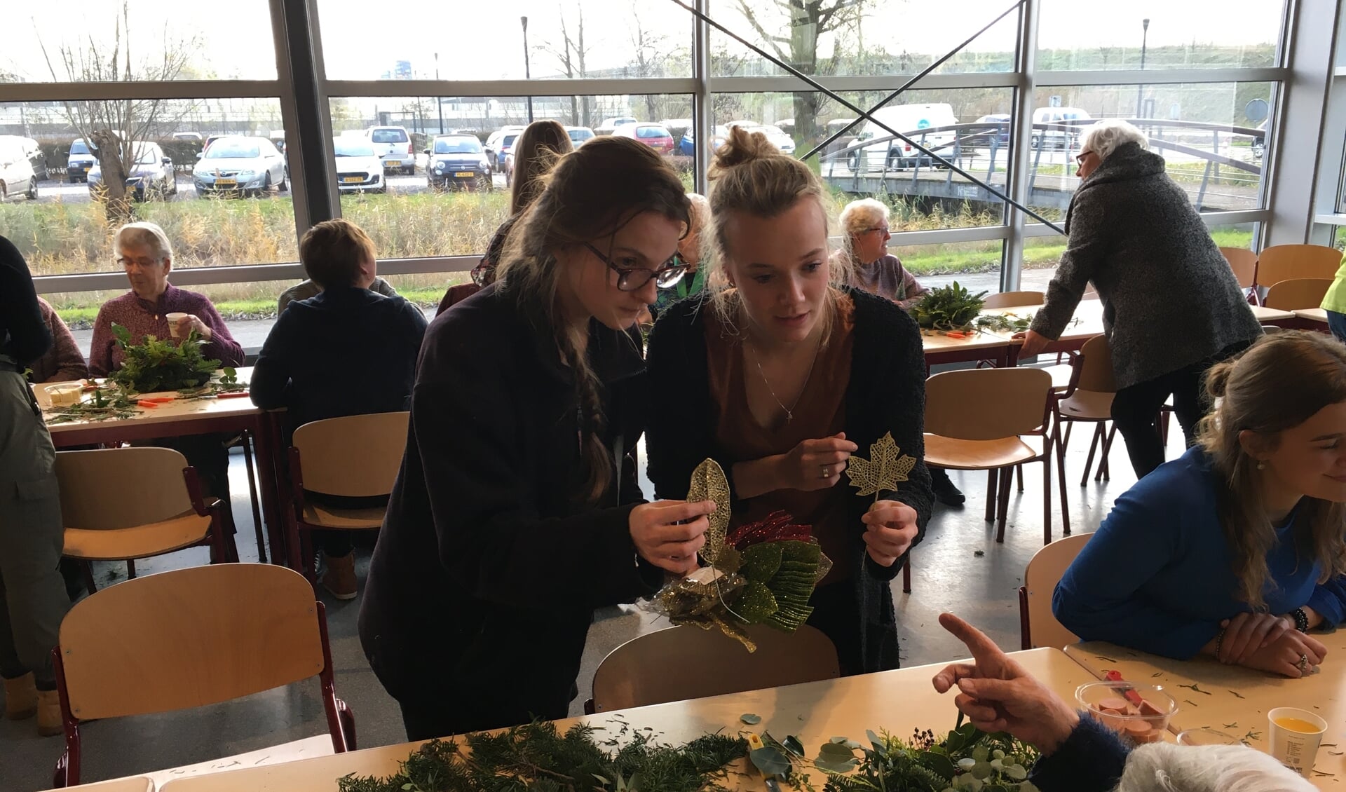 Werknemer van Tuincentrum Sterk en student Melanie helpen bij het maken van de kerststukjes 