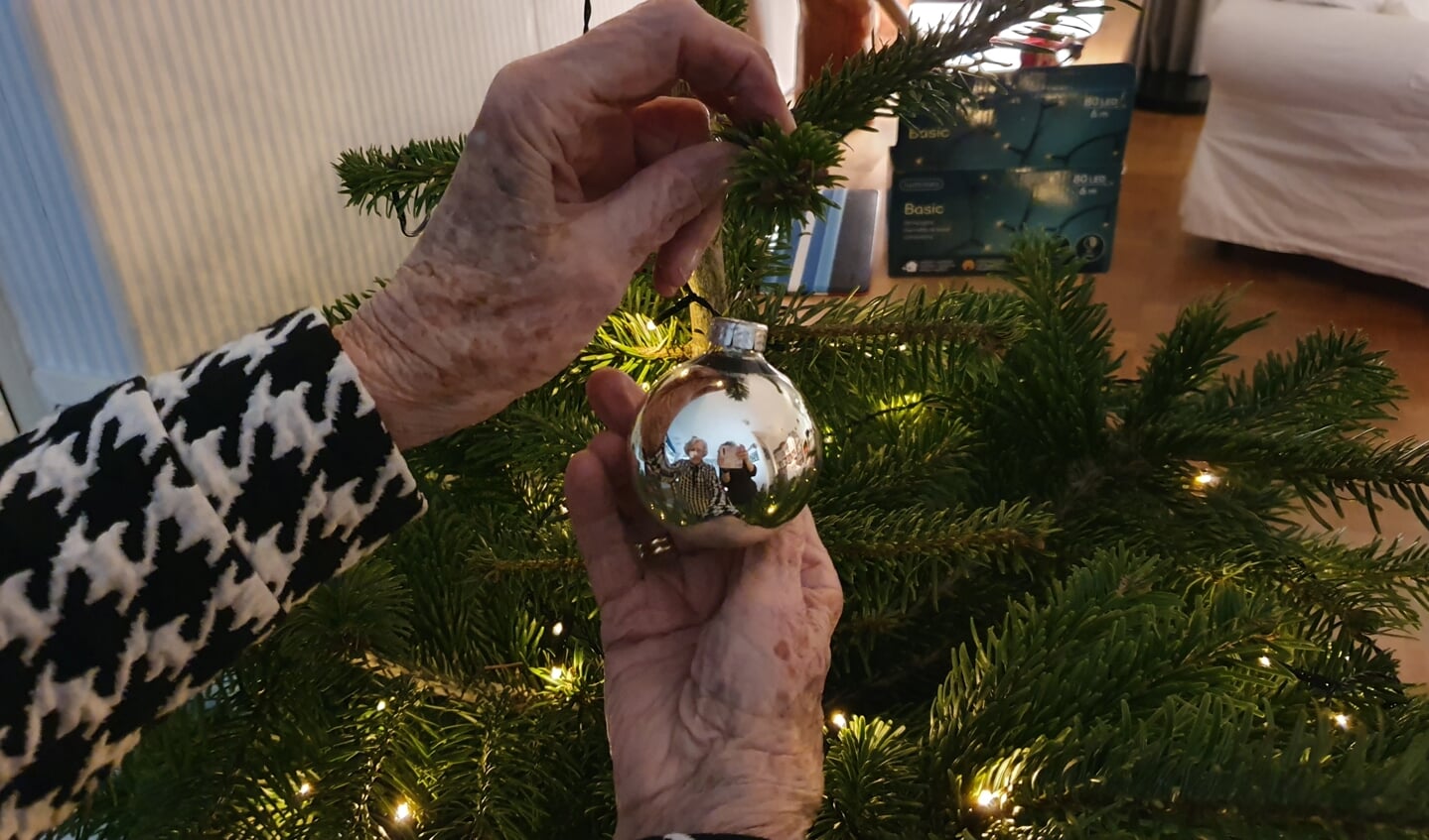 Dankbaar hangt Ans een kerstbal in haar nieuwe kerstboom