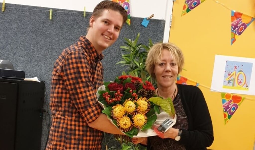 Juf Marja van Vuure neemt bloemen in ontvangst van directeur Patrick van den Hoorn