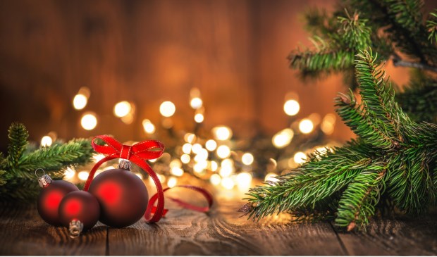 Red Christmas Ornaments on Wood Background and defocused lights. Spruce Tree branch on the left and right.