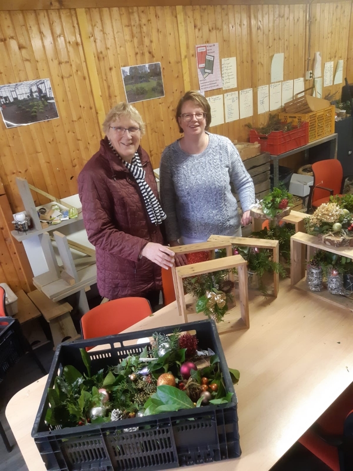 Vrijwilligers met kerststukje voor de voedselbank
