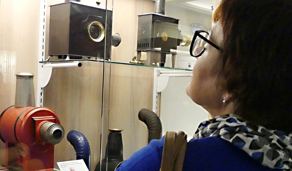 Een bezoeker bewondert een aantal toverlantaarns, die tentoongesteld zijn in het Kijk en Luistermuseum