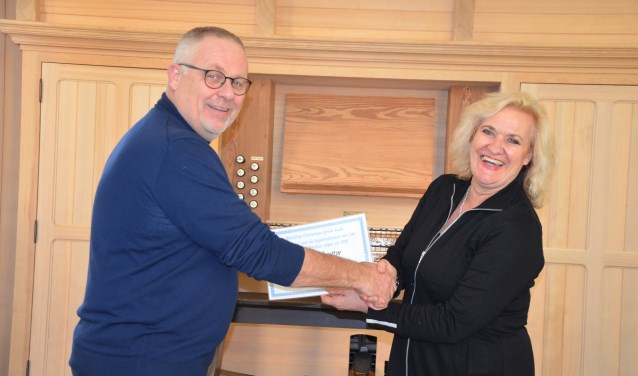 Wethouder Wil Kosterman overhandigt bij het orgel de cheque aan Sjoerd Vredenberg