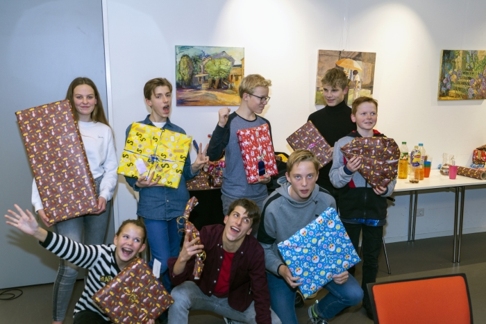 Een aantal deelnemers aan de actie poseren met en voor hun ‘buit’, nadat zij de hele stapel cadeaus hadden ingepakt.