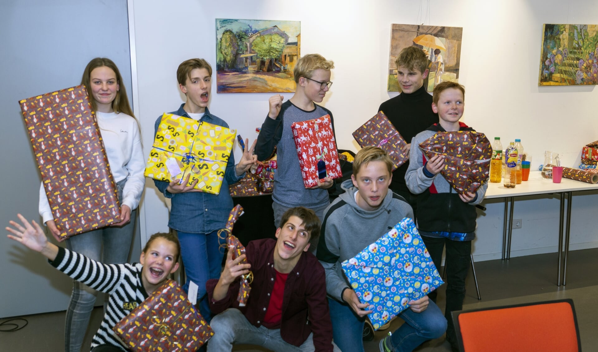 Een aantal deelnemers aan de actie poseren met en voor hun ‘buit’, nadat zij de hele stapel cadeaus hadden ingepakt.