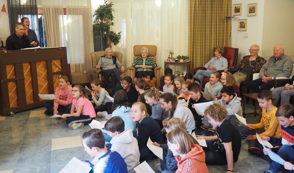 Kinderen van de Uilenburcht zingen, onder pianobegeleiding van Meester Dik, sinterklaasliedjes met de bewoners van Rehoboth.
