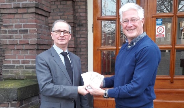 De voorzitter van Rotary Velsen, Jan Willem Bruntink, overhandigt de kaarten aan de directeur van het Vellesan College, Marc Boelsma.
