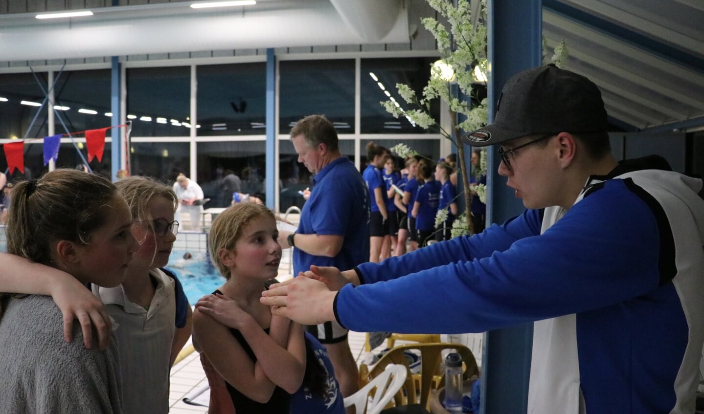 Trainer Hans Stoffers geeft de zwemmers tips voordat ze hun afstand gaan zwemmen